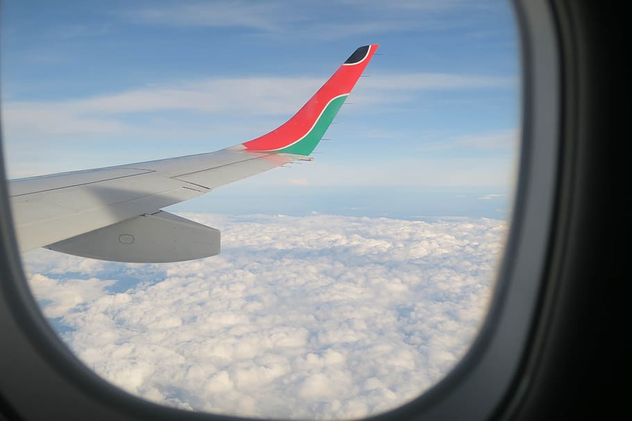 white, pink, and green airplane window viewed from a window, white, red, and green airplane wing under blue sky during daytime HD wallpaper