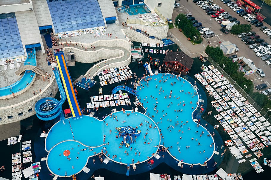 aerial photography of swimming pool near parking lot, aerial view of group of peoples on swimming pool