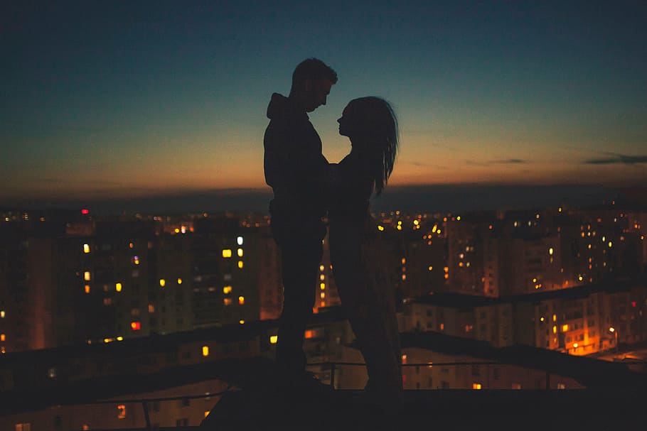 silhouette of man and woman standing on top of building, people