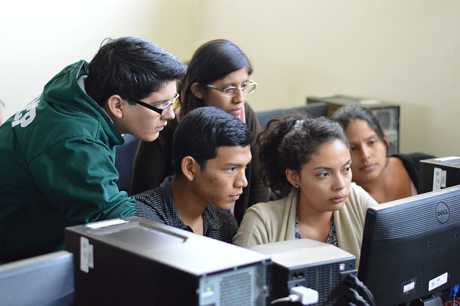 five people sitting and standing in front of computer, student