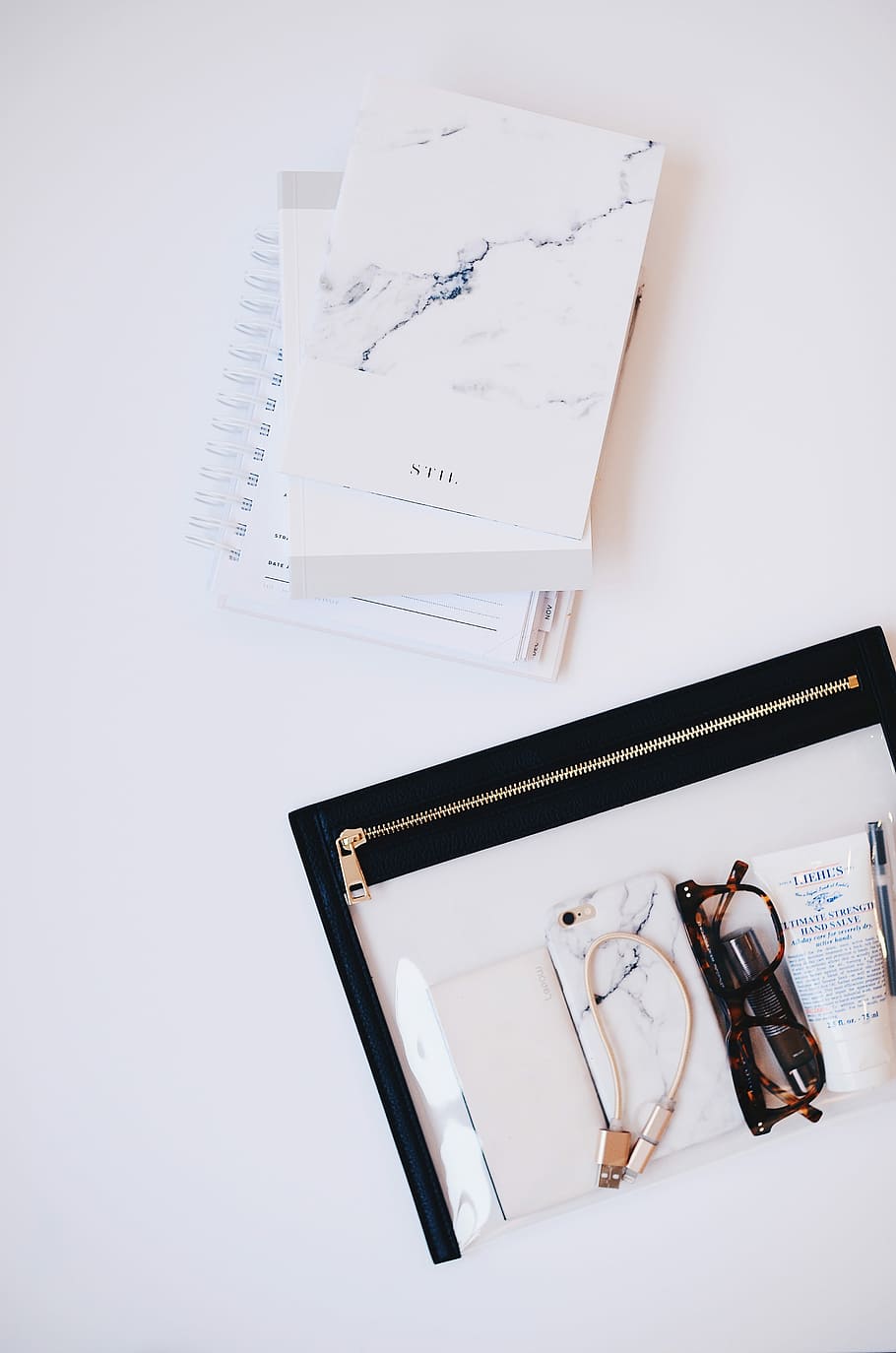 clear eyeglasses with brown frames in clear and black pouch, three books next to black pouch with smartphones and eyeglasses HD wallpaper