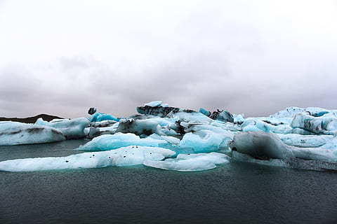 teal ice berg during daytime, ice burgs on ocean under white clouds HD wallpaper