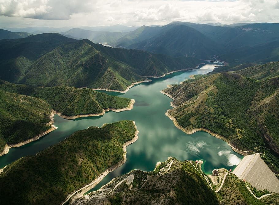 bird's eye view of river surrounded by mountains, aerial photography of body of water surrounded by green mountains