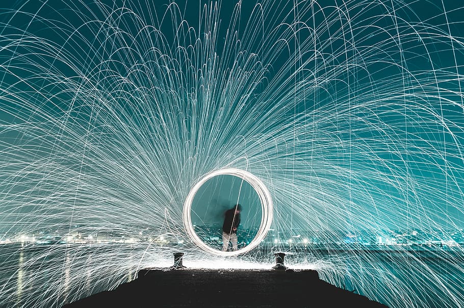 man standing on dock steel wool photography, steel wool photography of man on wooden dock between body of water HD wallpaper