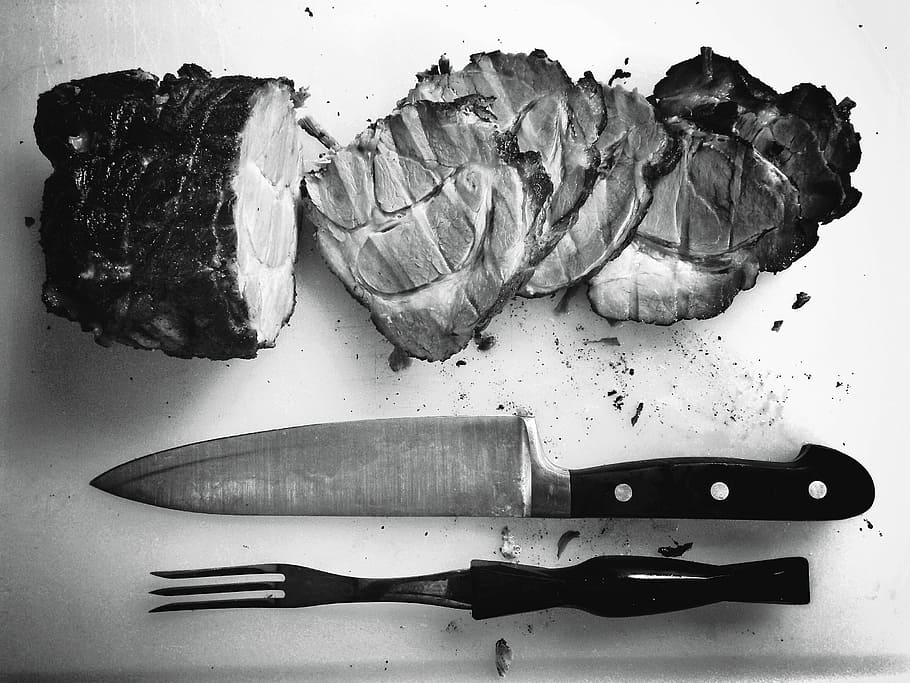 grayscale photo of grilled meat beside knife and fork, sliced meat beside kitchen knife and tong on chopping board HD wallpaper