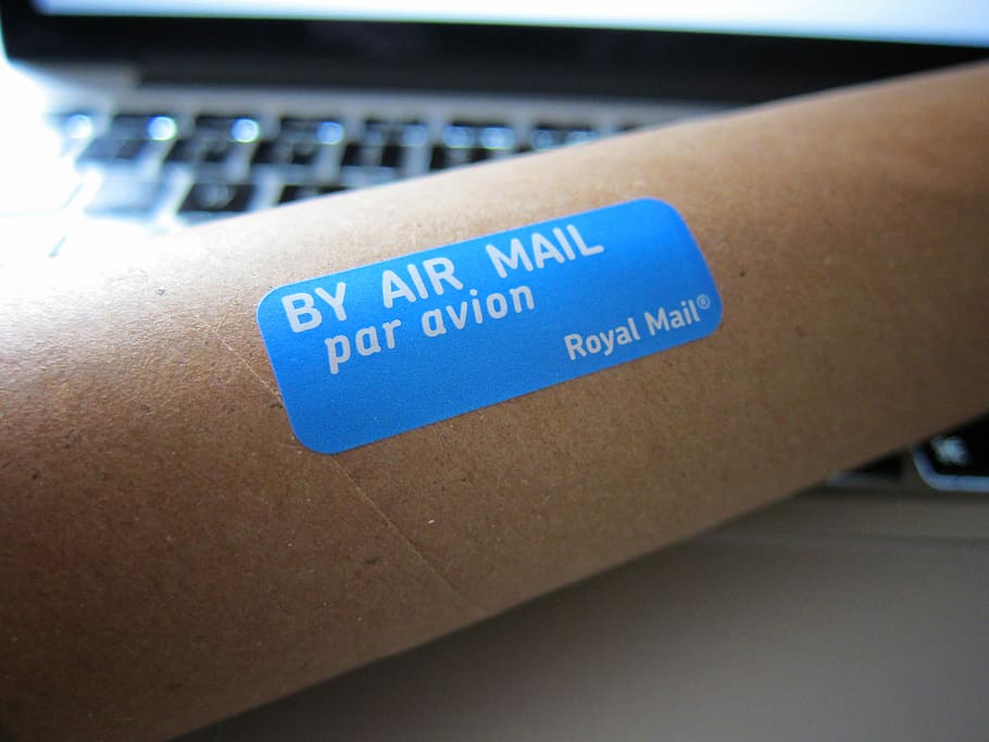 blue air mail sticker on brown surface, blue paper with By Air Mail text-printed