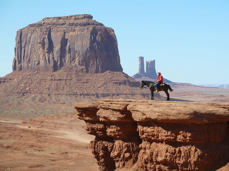 man riding on horse near rock cliff near canyon, monument valley