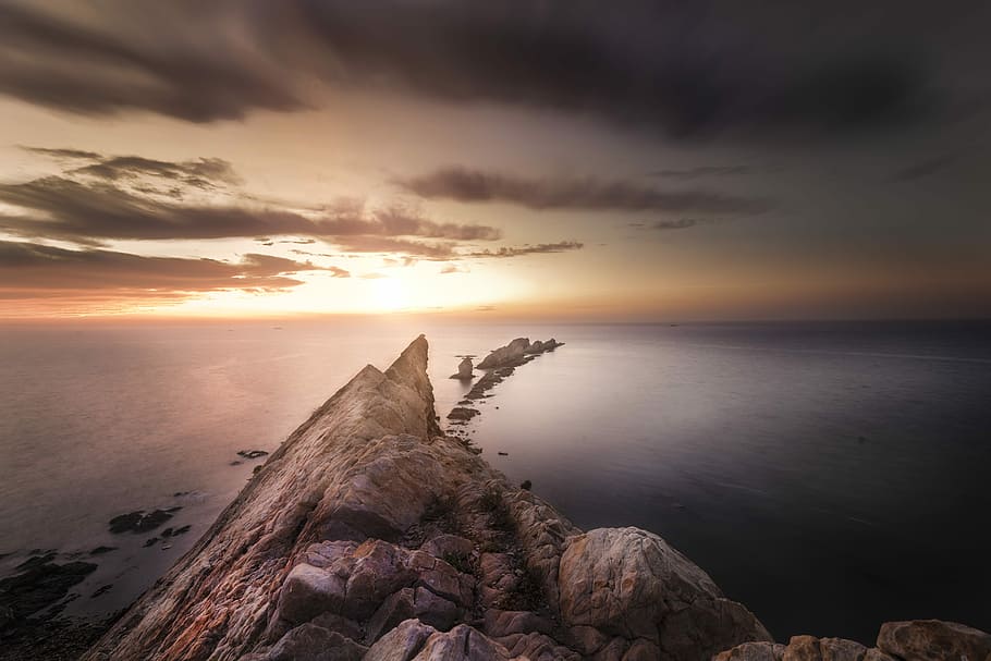 brown rock formation during sunset, body of water under clouds HD wallpaper