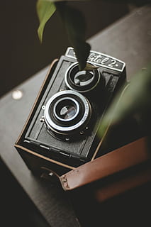 black box camera on brown panel, vintage black and gray camera inside case on brown wooden table selective focus photography HD wallpaper