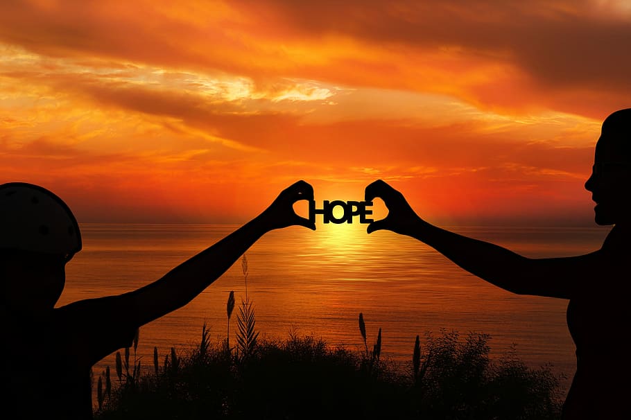 silhouette of people holding HOPE logo during sunset, forward