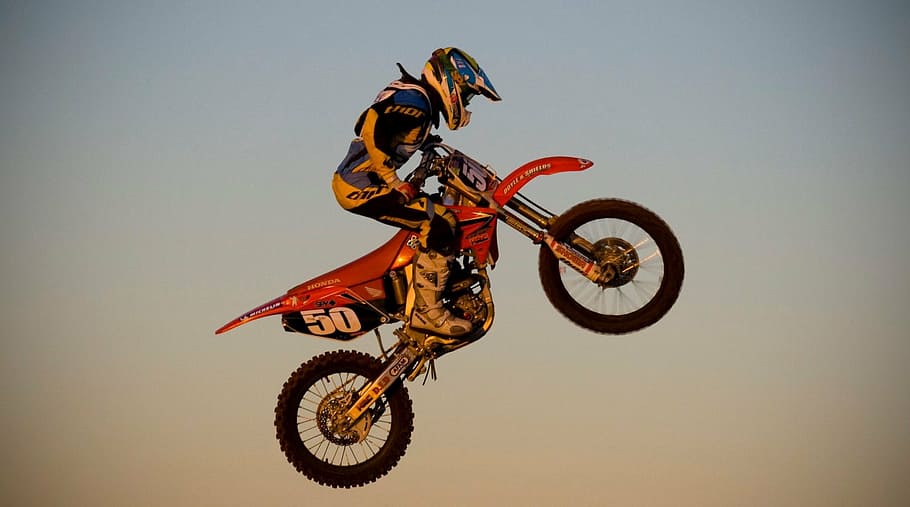 photo of person riding red motocross dirt bike, motorbike, motorcycle