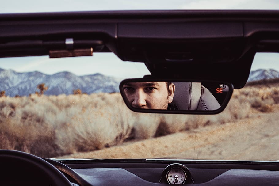 person staring at rear view mirror, man looking at the vehicle rear mirror