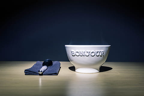 Bonjour Embossed White Ceramic Bowl on Table Beside Stainless Steel Spoon on Black Table Textile HD wallpaper