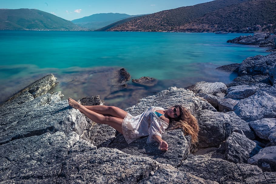 woman lying on gray rock near lake, woman laying on boulder near body of water, HD wallpaper