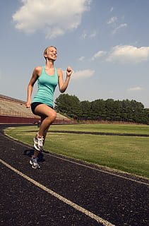 women in blue tank top running on track field during daytime HD wallpaper