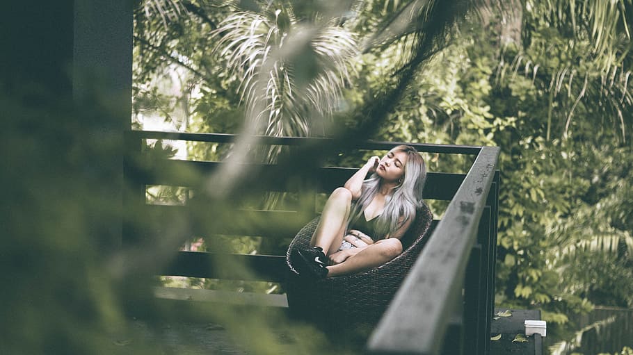 woman sitting on brown wicker egg chair, woman wearing green sleeveless top across woods HD wallpaper