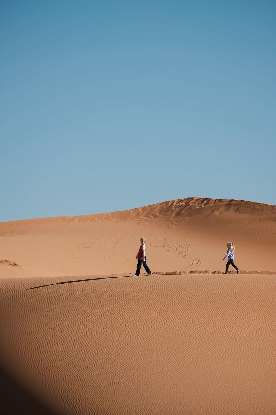 man and woman walking on brown sands, girl and boy walking on desert under blue sky HD wallpaper