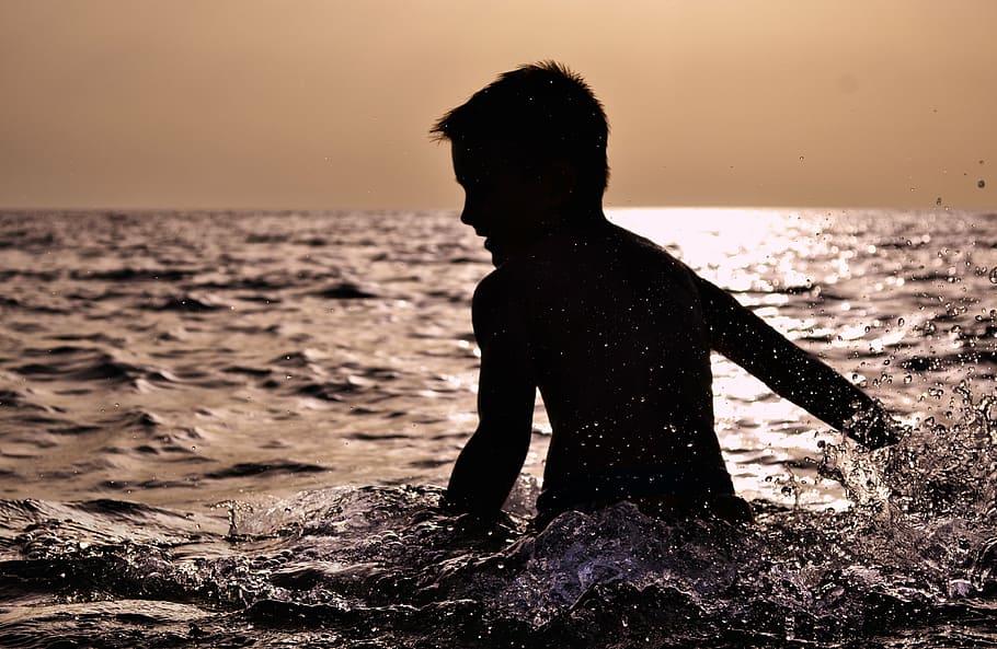 silhouette of boy swimming during sunset, toddler, splashing around