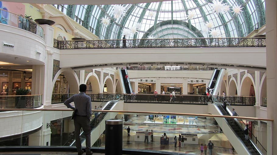 man looking below the ground while inside the room, shopping mall