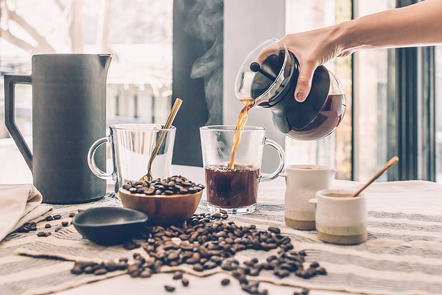 shallow focus photography of person pouring coffee on clear glass mug HD wallpaper