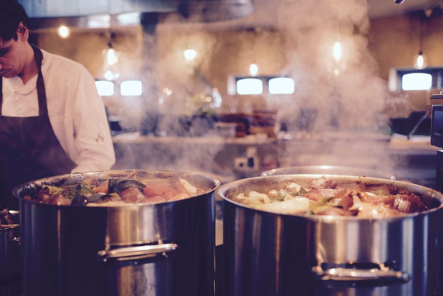 man standing beside two silver pots with boiling water with food HD wallpaper