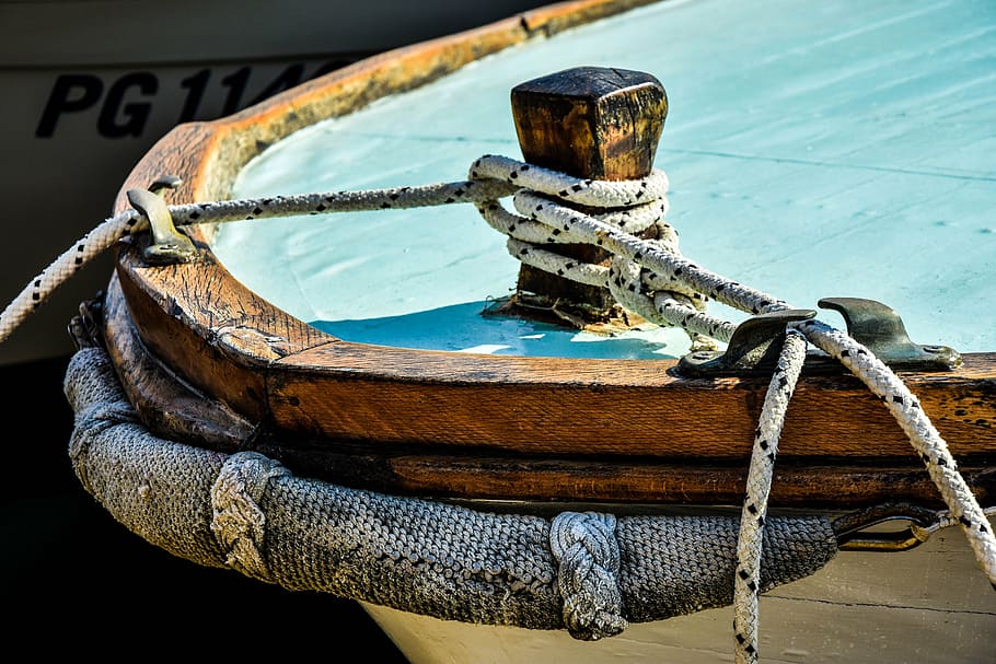 white and brown boat with gray rope parked at daytime, wooden boat