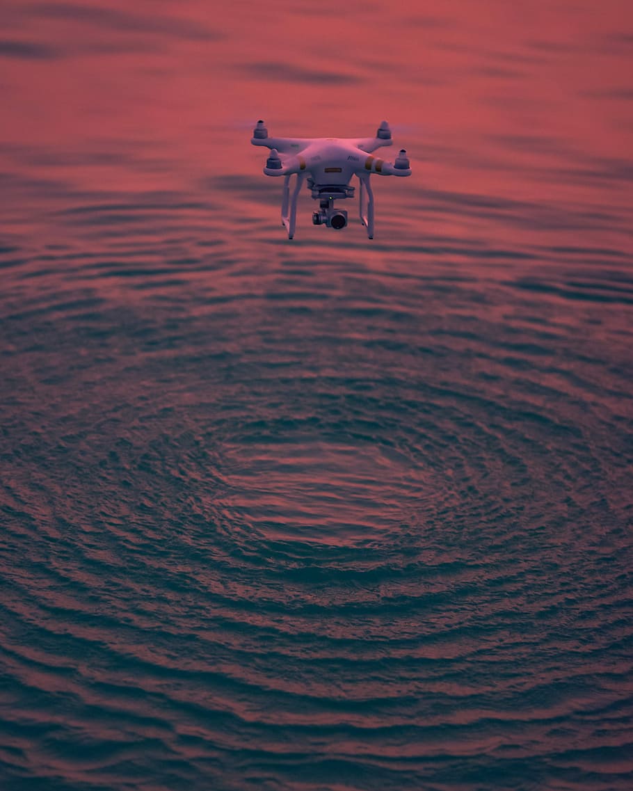 photography of quadcopter drone flying above body of water HD wallpaper