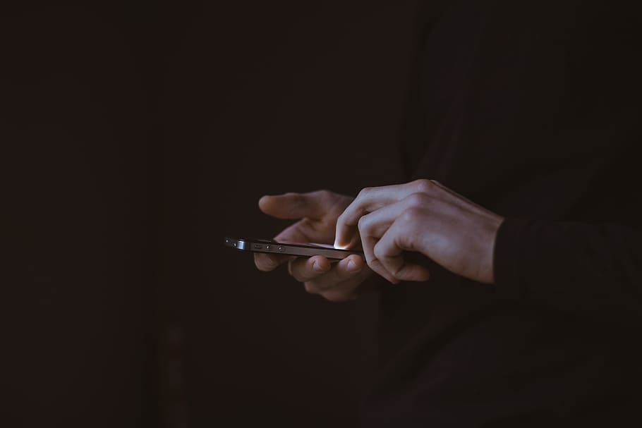 man holding iPhone, dark, people, guy, texting, mobile, electronic HD wallpaper