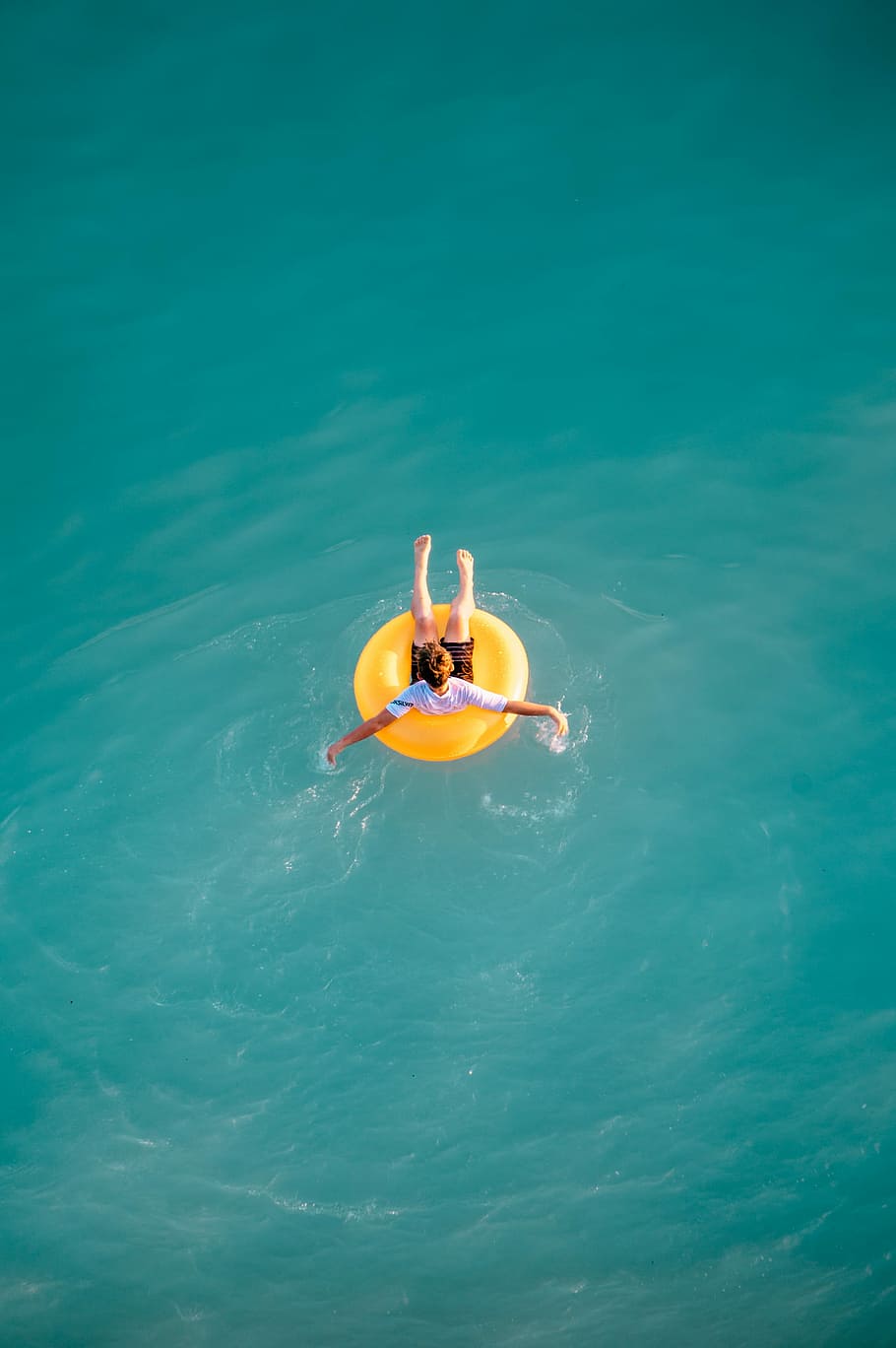 boy sitting on buoy, boy riding yellow life buoy on body of water during daytime HD wallpaper