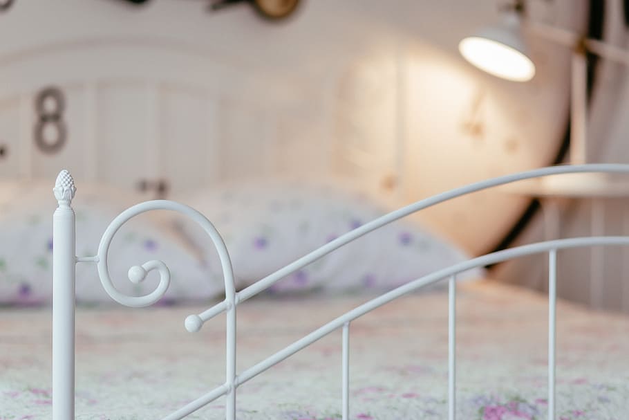 selective focus photography of white metal footboard, bed, pillow