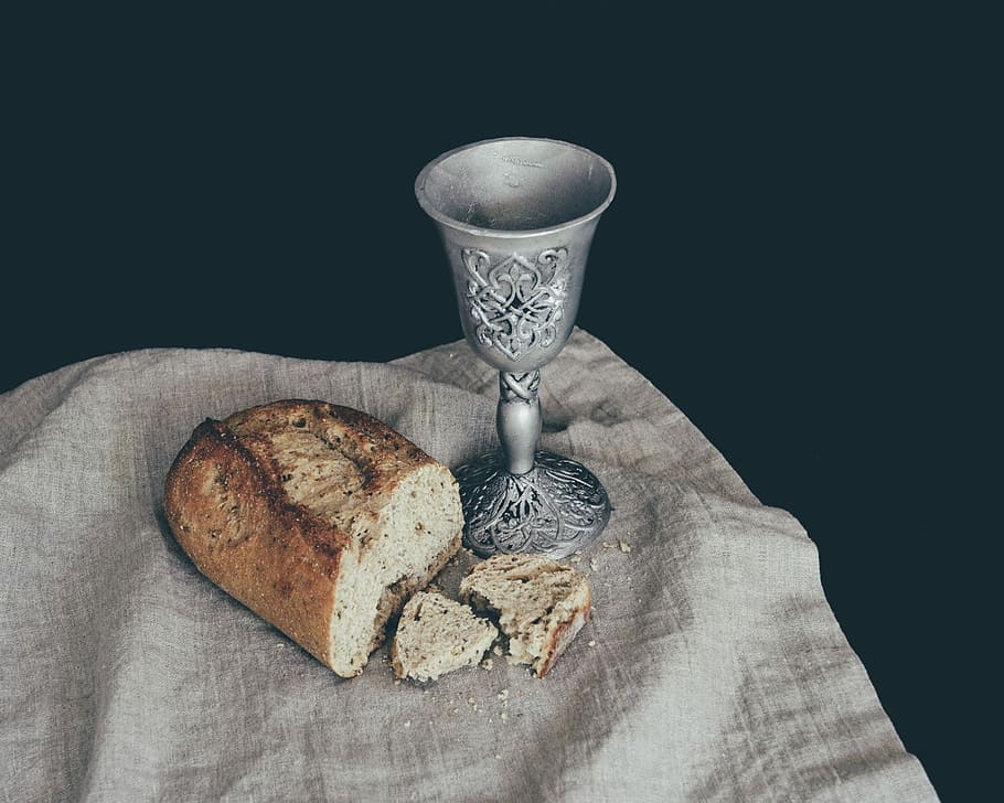 sliced of bread beside goblet, gray steel cup beside sliced bread
