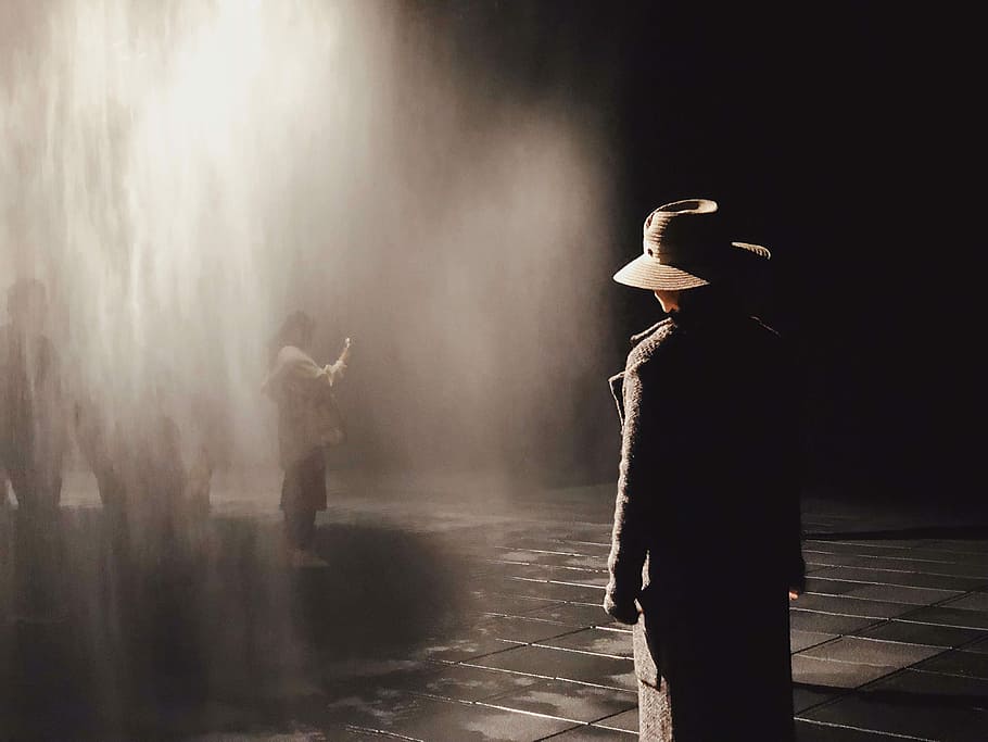 man standing in front of water, person wearing black coat standing near woman with light passing through HD wallpaper