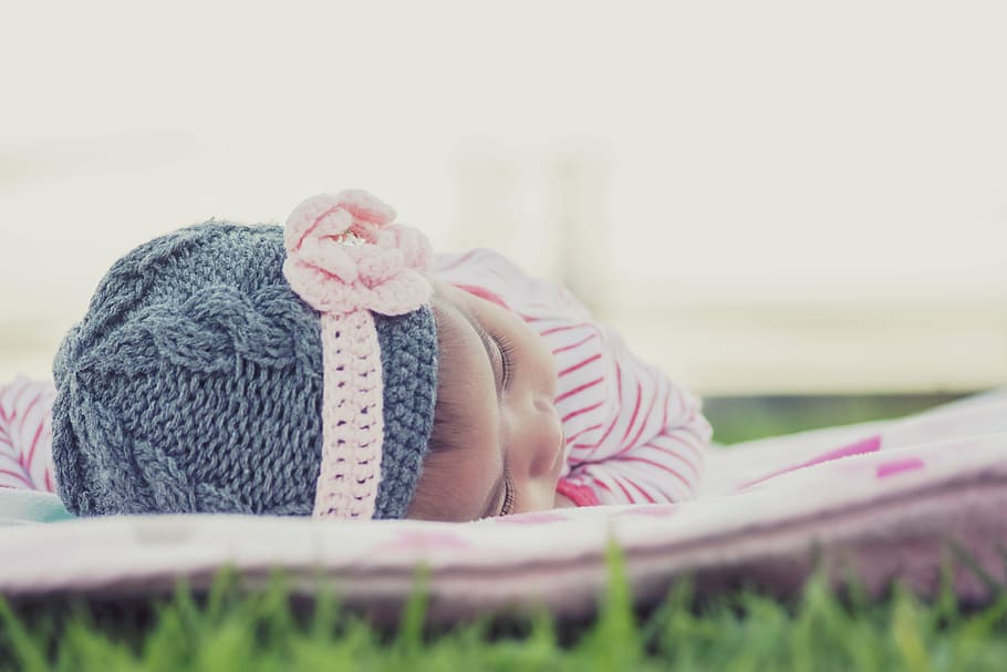 baby's wearing gray knitted cap and pink footies, lay down HD wallpaper