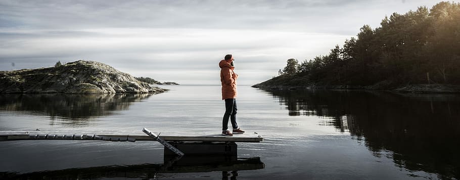 person standing on bridge, mam standing on dock in middle of body of water during daytime HD wallpaper