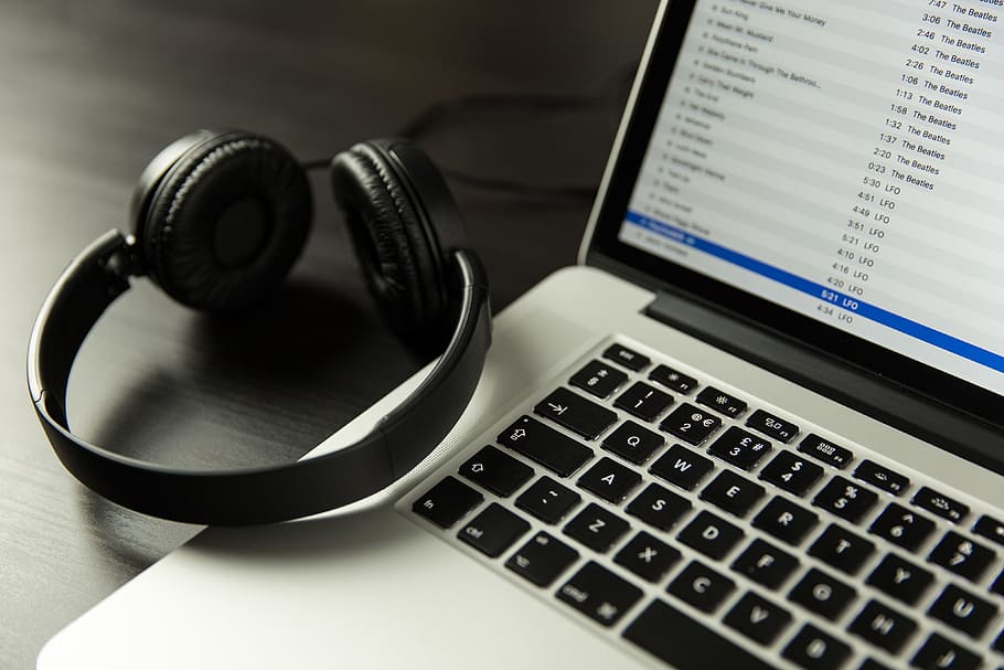 iTunes music app open on a laptop computer alongside headphones, HD wallpaper