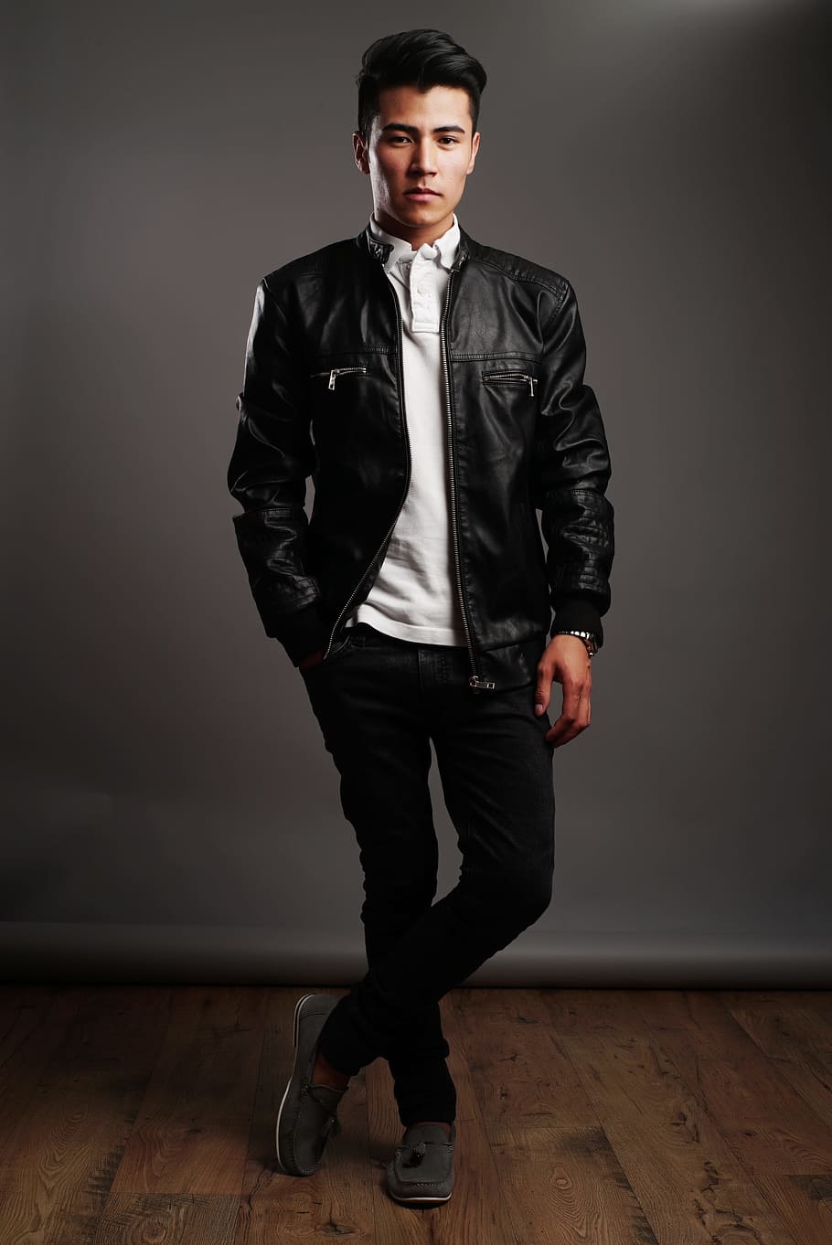 man in black leather jacket, white shirt, and black pants, straight looking
