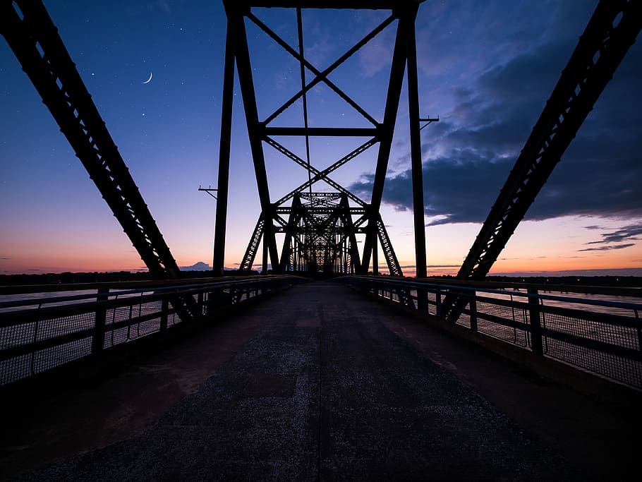 photo of suspension bridge, black metal bridge above sea under gray clouds HD wallpaper