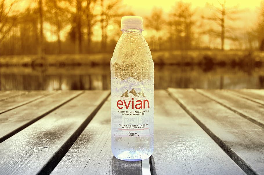 500 ml Evian water bottle on brown wooden surface, still, drink