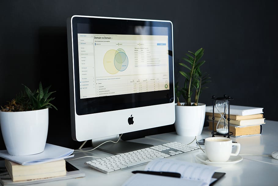 silver iMac near the white keyboard and a cup of coffee, desk HD wallpaper