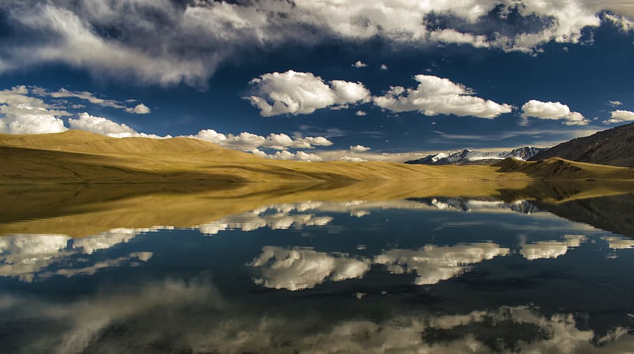 calm body of water near sand under white clouds, mountain ranges under cloudy sky HD wallpaper