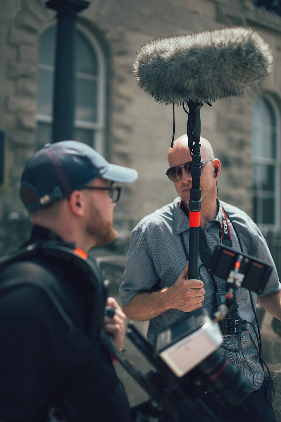 men getting ready to shoot a movie film, man holding microphone talking to man in black polo shirt