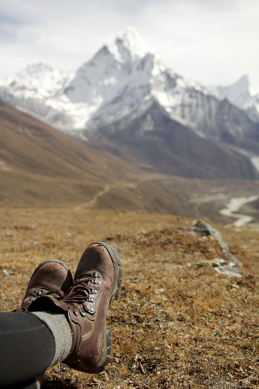 depth of field photography of person wearing brown leather hiking boots in front of mountains during daylight HD wallpaper