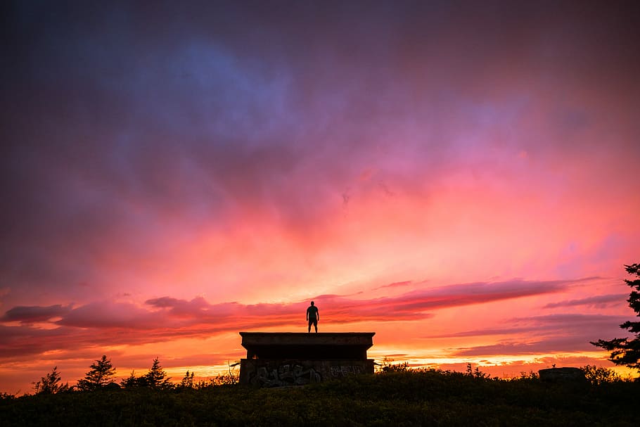 silhouette of person standing on the roof of the house, man standing on building during sunset