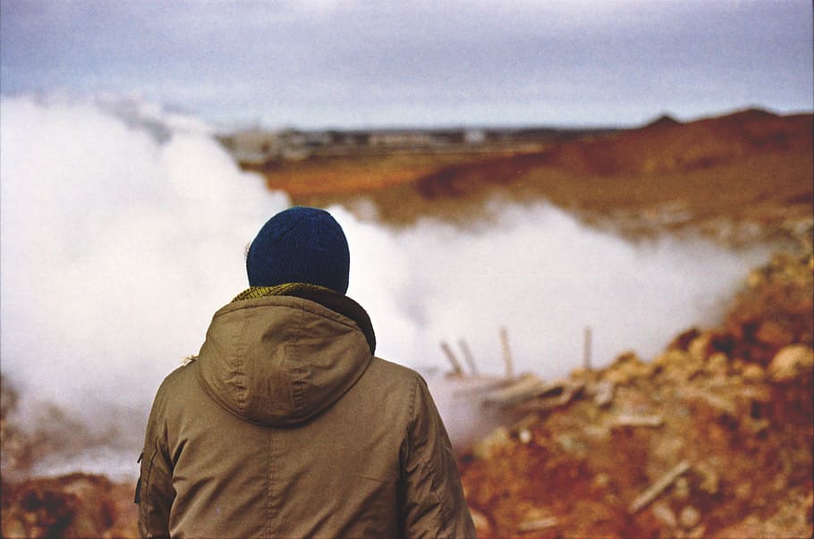person in brown hooded jacket standing near fog, person looking on body of water HD wallpaper