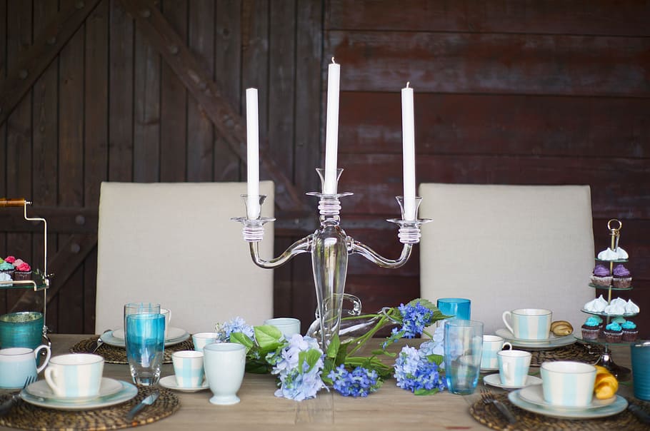 clear glass candle holder on top of table near cup and saucers