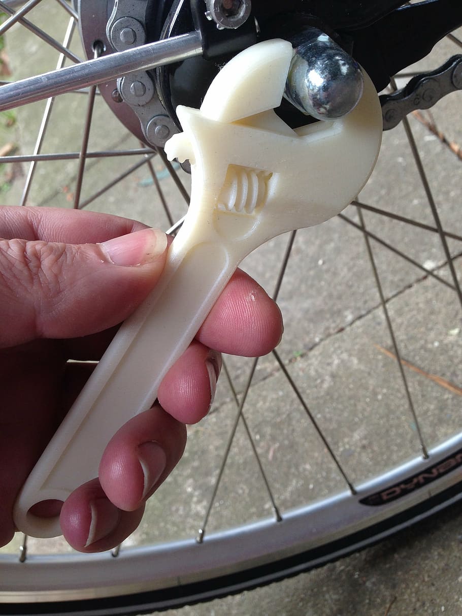 person turning bolt on bicycle using adjustable wrench, 3d printing