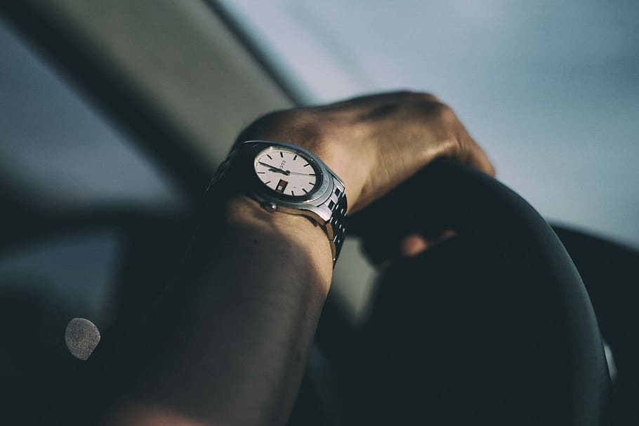 person wearing silver-colored watch holding steering wheel HD wallpaper