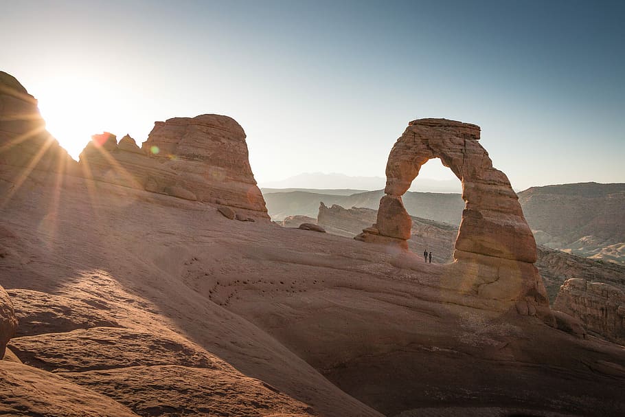 two people under stone formation, rock formations under clear blue sky during daytime HD wallpaper