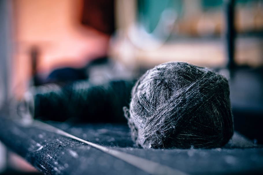 A ball of yarn besides spools of thread and fabric, black wool in black surface HD wallpaper
