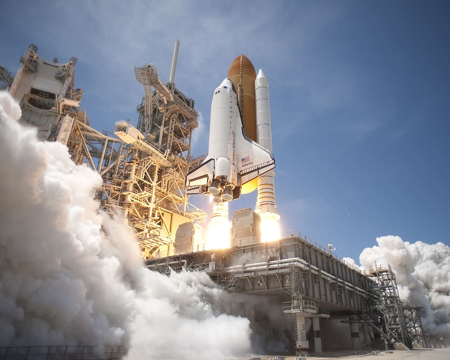 white and brown space shuttle launch under blue sky during daytime